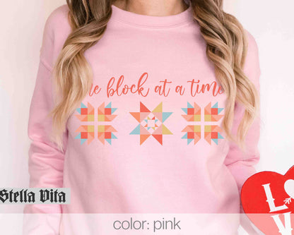a woman wearing a pink sweater with the words be block at time on it