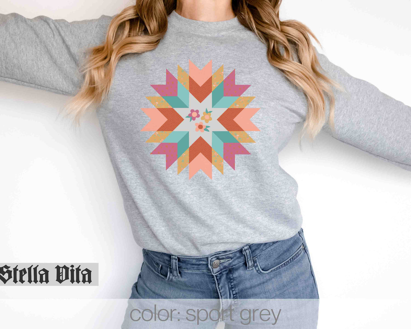 a woman wearing a grey sweater with a colorful flower on it