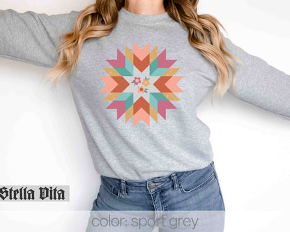 a woman wearing a grey sweater with a colorful flower on it